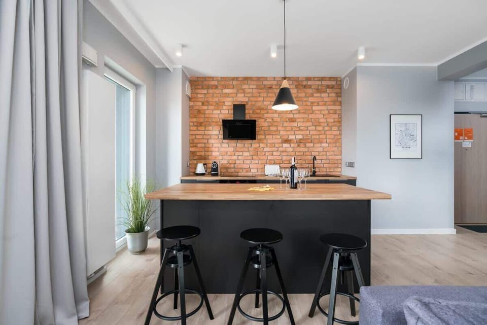 A fully-equipped kitchen with black cabinetry, a brick backsplash, and essential appliances placed along the countertop.