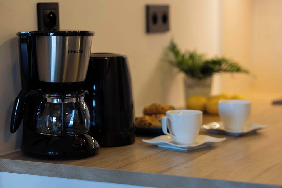 A compact coffee set with a black coffee machine and cups, ideal for enjoying your morning brew.