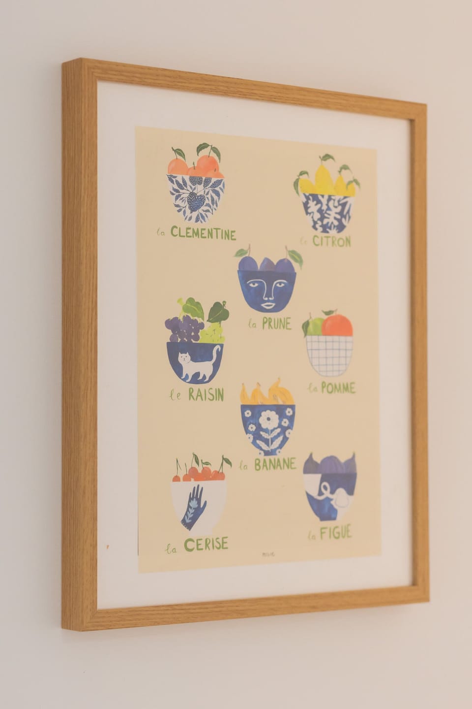 A framed picture of colorful floral artwork hanging on a white wall. The frame is simple, allowing the art to stand out.