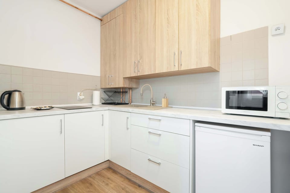 A clean and practical kitchen with wooden countertops, white cabinetry, and essential appliances including a microwave and a stove.