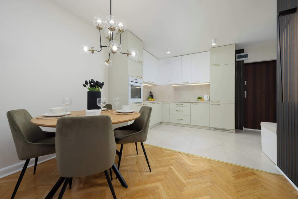 A dining table with four chairs next to a modern kitchen with built-in appliances.