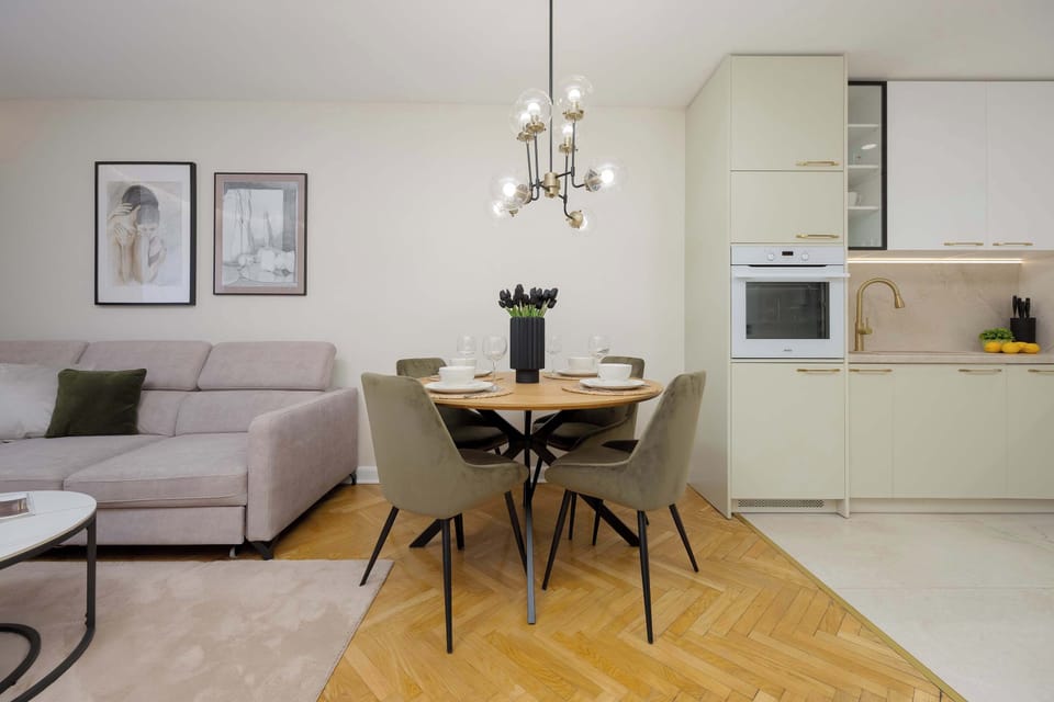 A dining table with four chairs next to a modern kitchen with built-in appliances.