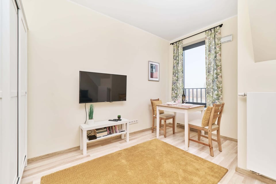 Living area with a large window, green curtains, TV and modern furnishings.