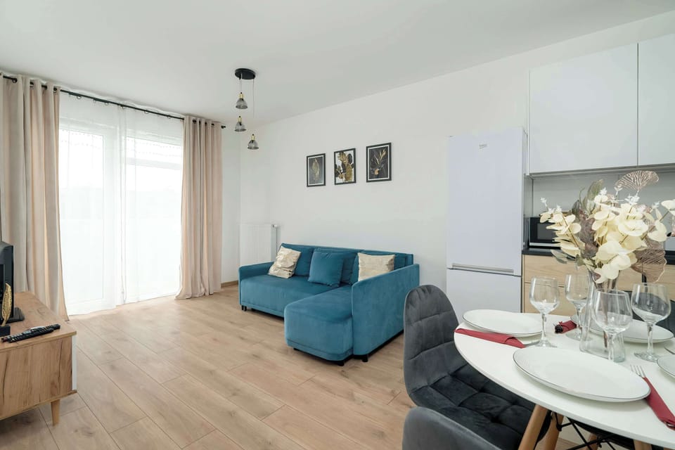 Another view of the living room with a blue sofa and light-filled windows, creating a spacious, airy feel.