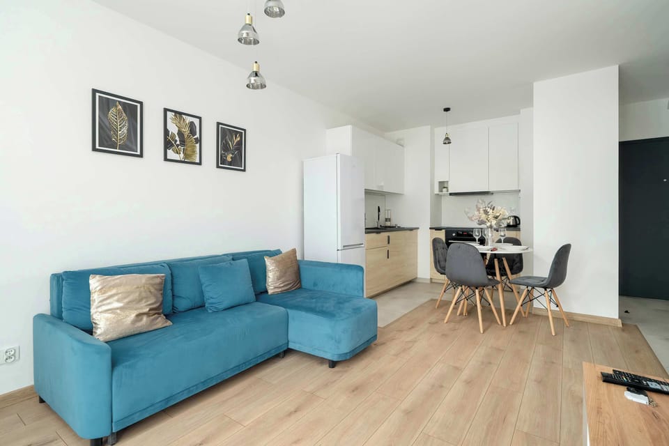 An open-plan living space with a blue sofa and a modern kitchen in the background, creating a versatile layout.