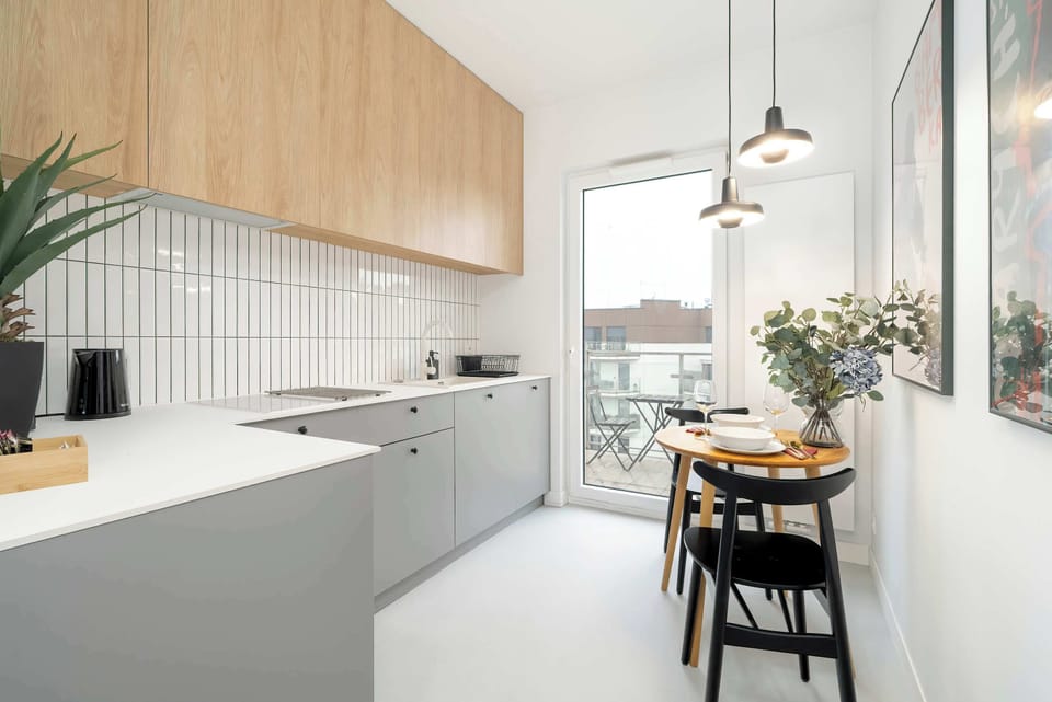 Functional kitchen with dining space with a wooden table, designer chairs, and a beautiful view from the window, perfect for hosting meals.