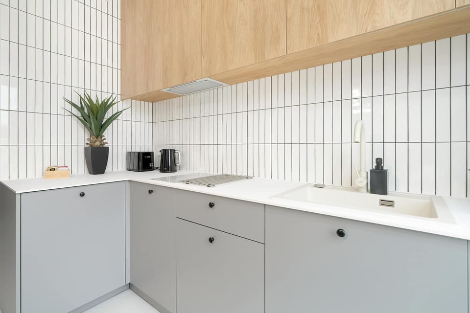  A functional and modern kitchen featuring wooden cabinetry, white tile backsplash, and stainless steel appliances.