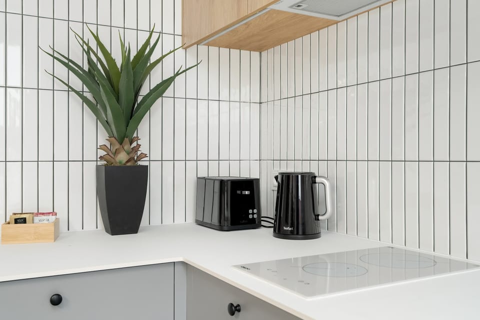  A sleek kitchen setup with clean white surfaces, wooden accents, and potted plants for a refreshing feel.