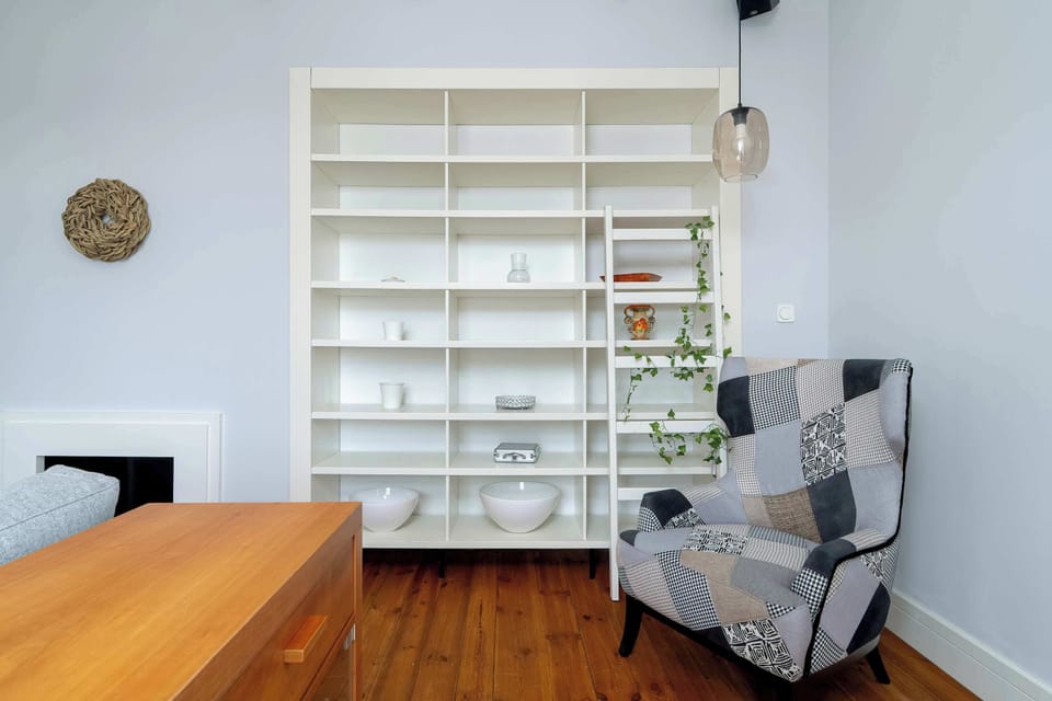A view of the same living area highlighting built-in shelves, a reading corner with a patterned armchair, and subtle decorative accents.