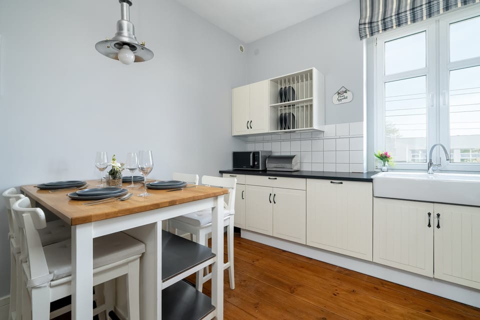 A close-up of the kitchen dining area under pendant lighting, next to a window framed with striped curtains.