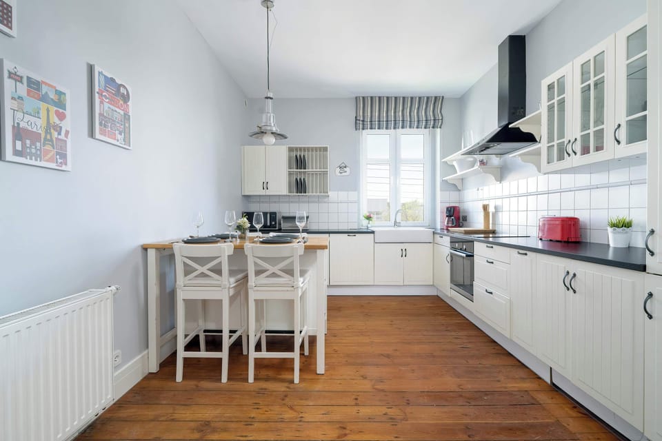 A different angle of the kitchen with four  chairs at the table, giving a sense of space and light within the room.