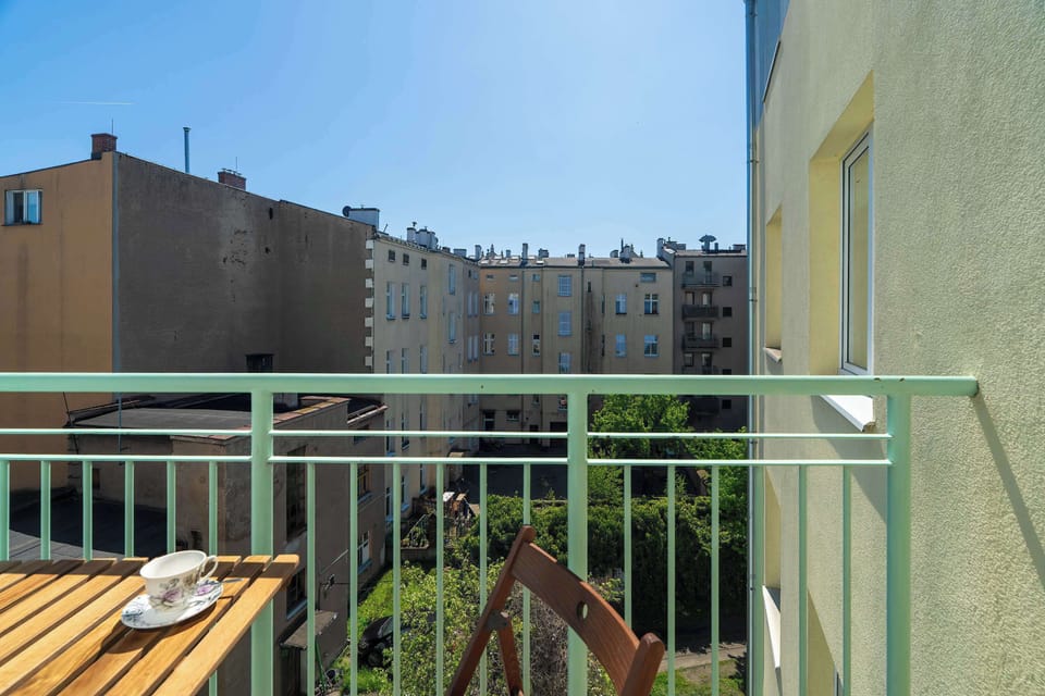 A balcony offering a view of nearby residential buildings, with a small wooden table and chairs for outdoor relaxation.