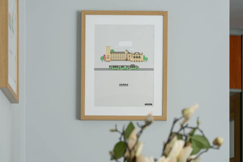 A framed artwork above a small table with flowers, capturing a close-up view of interior wall decor.