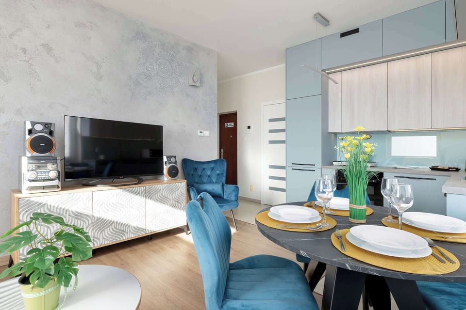 A bright living area with a blue sofa, yellow throw, and a large clock on the wall.