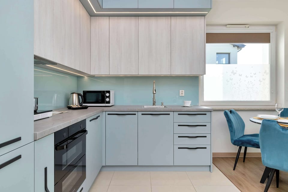 A sleek kitchen with light wood cabinets and built-in appliances.