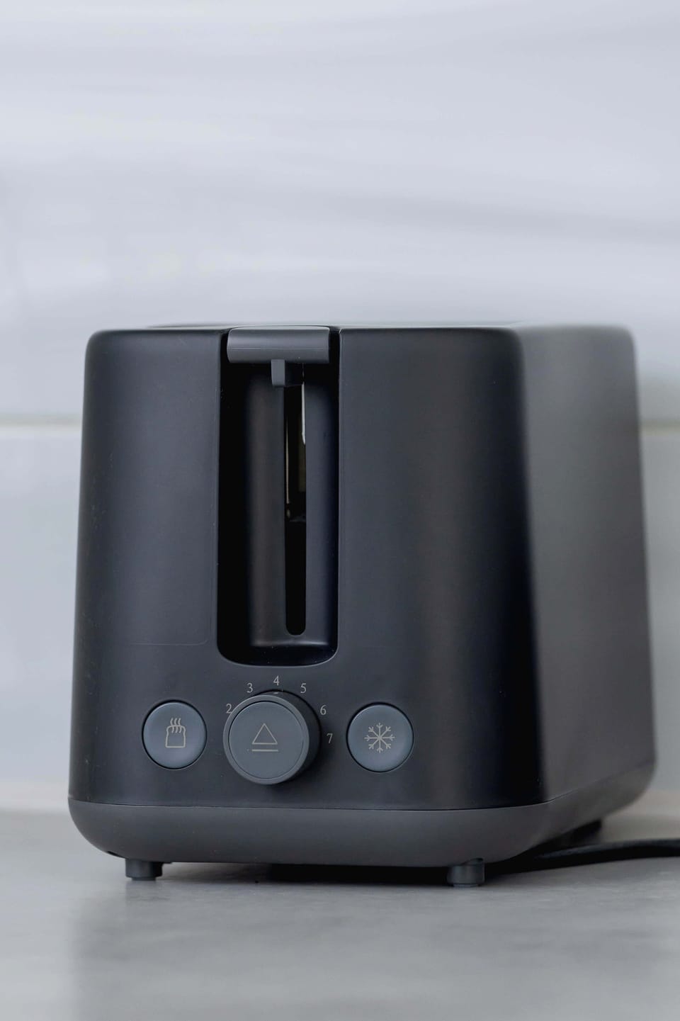A close-up view of the toaster, featuring a sleek, black finish that complements the modern kitchen decor. It provides an essential appliance for quick meals.

