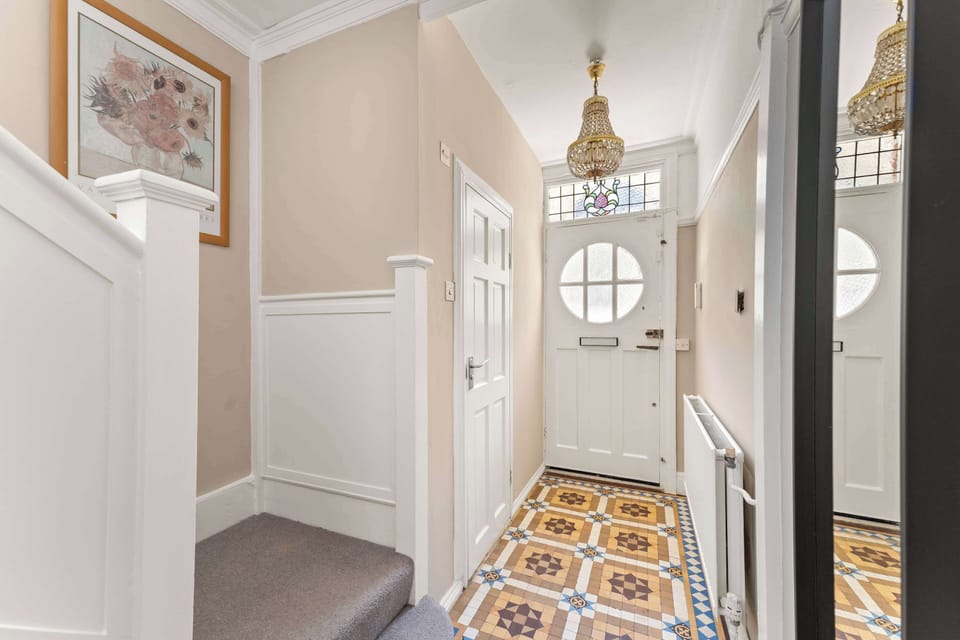 Traditional patterned floor tiles and a classic white door with circular glazing create a bright and welcoming first impression.