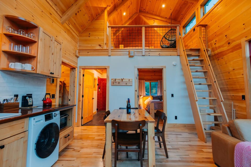 Interior of the Cherry Cabin, showing the dining area, loft ladder, bedroom, and tiled bathroom beyond.
