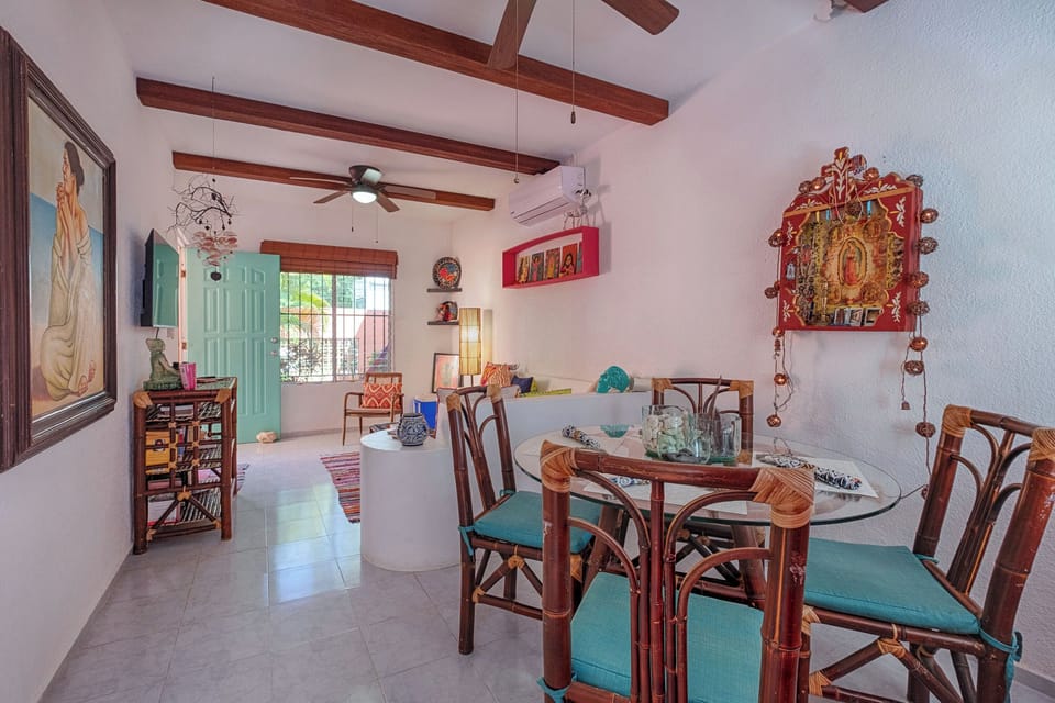 In this gorgeous and vibrant tropical home, the dining and living areas flow effortlessly together. The charming rattan furniture and stunning folk art create an artistic atmosphere, perfectly cooled by the wall-mounted AC.