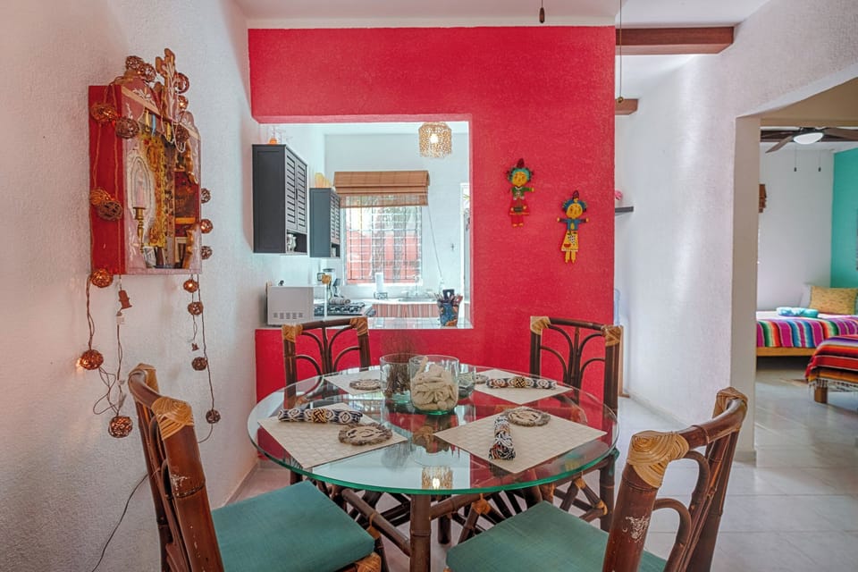 Enjoy meals in this charming dining nook, highlighted by a striking red accent wall and gorgeous rattan chairs with plush cushions. The round glass table and decorative lighting create an intimate and unforgettable tropical dining experience.