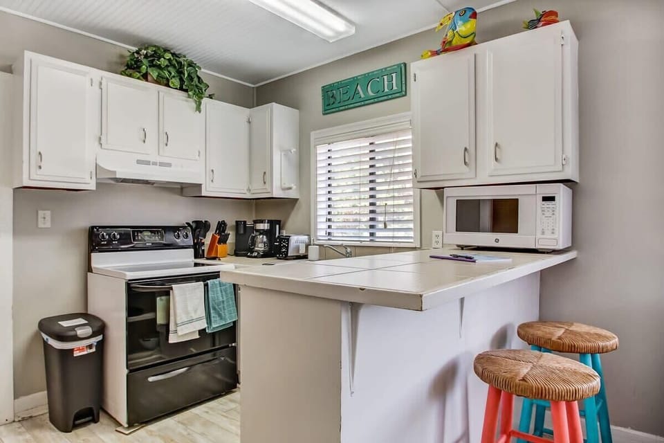 Updated kitchen with white cabinetry and breakfast bar seating.