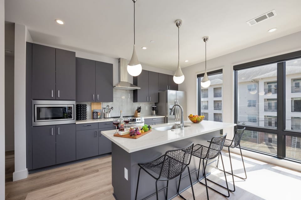 Unit 1: Fully equipped kitchen stocked with basic cooking essentials. Includes stainless steel appliances and kitchen island seating.