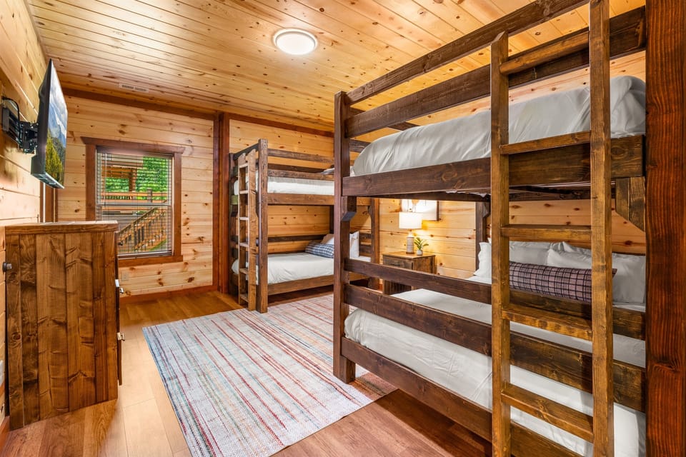 Bunk room with a queen-over-queen bunk, a twin-over-twin bunk, TV, and ensuite bath.