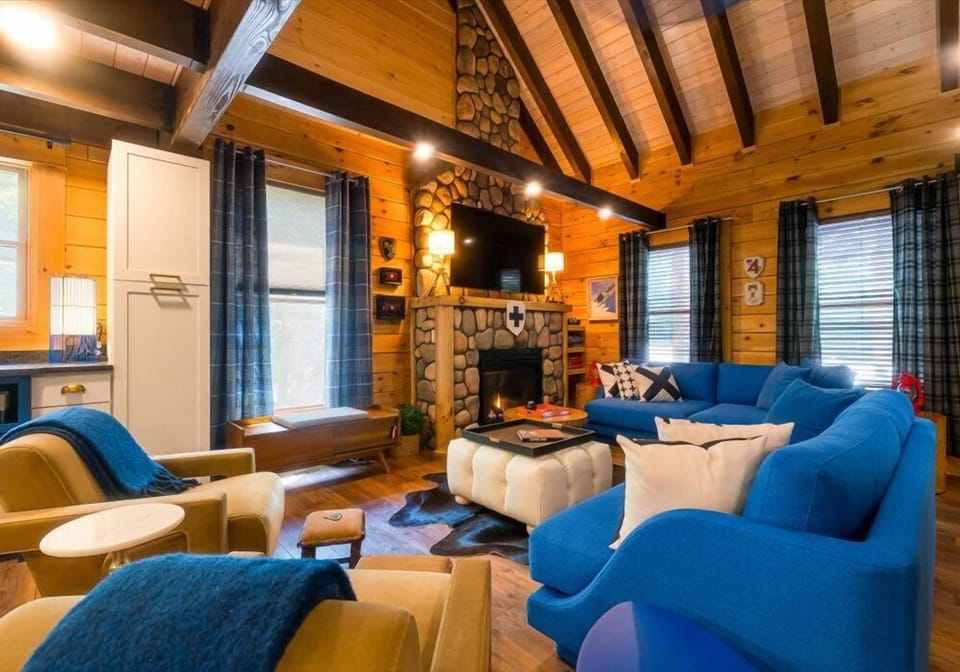 Enjoy the cozy glow of the gas fireplace, surrounded by rich timber accents, log beams, and warm wood-paneled walls. Relax on the plush sofa in the open concept living area, thoughtfully styled with designer touches throughout