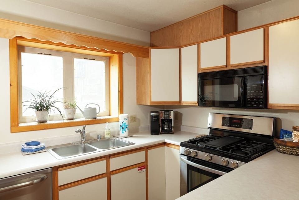 Your fully equipped kitchen features modern appliances and plenty of counter space, making it easy to prepare meals while enjoying natural light streaming through the sunny window above the sink.