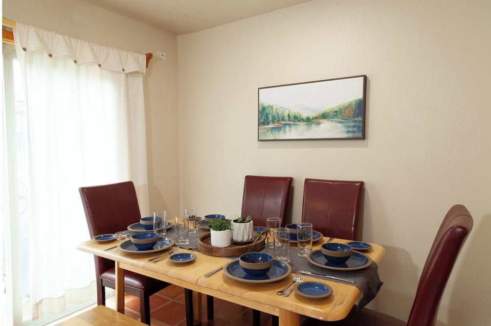 Gather around a beautifully set dining table with charming blue dinnerware and natural light filtering through the window. Your perfect space for memorable meals together.