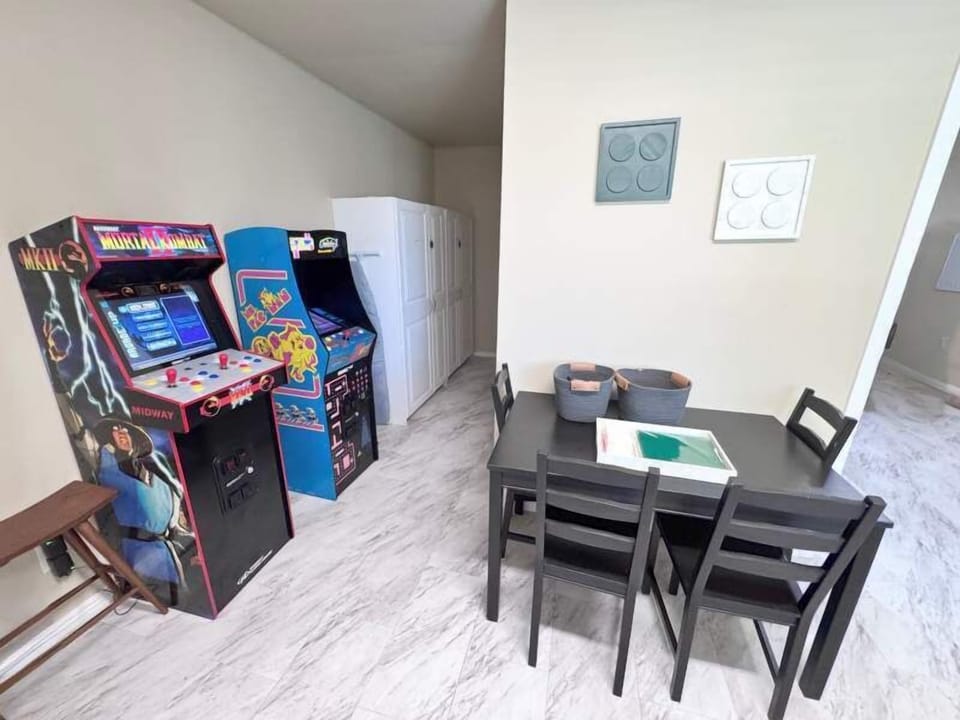 Two arcade machines and small dinner and play table in the game room