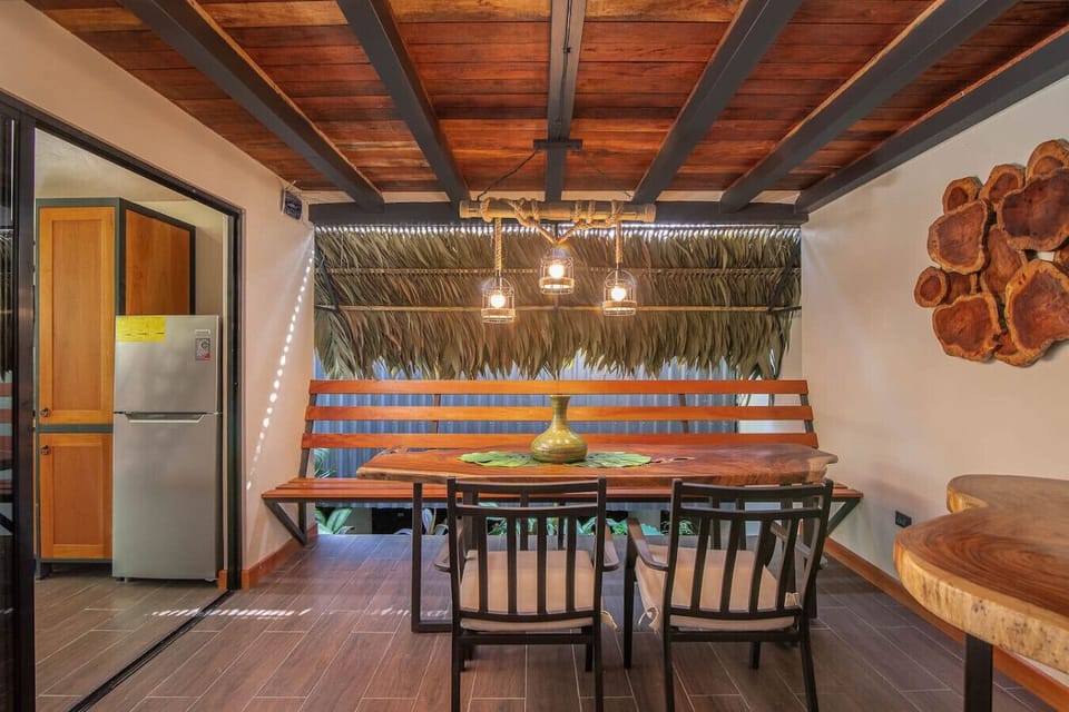 Spacious covered terrace with solid wood dining table and tropical design, perfect for indoor-outdoor living at Aloki Kiré 2 in Playa Chiquita, Costa Rica