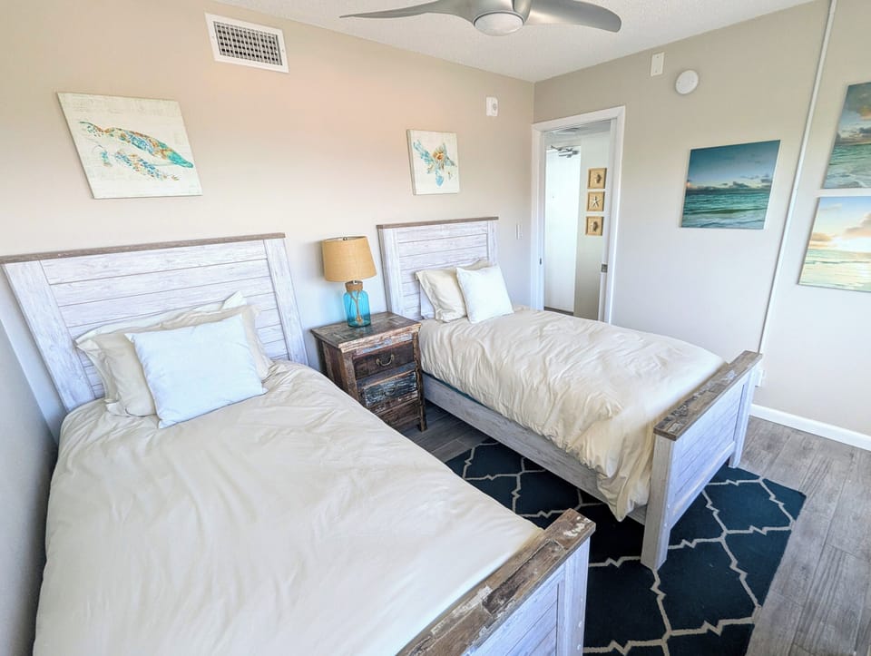 Cozy secondary bedroom with twin beds, ceiling fan, and plenty of natural light.