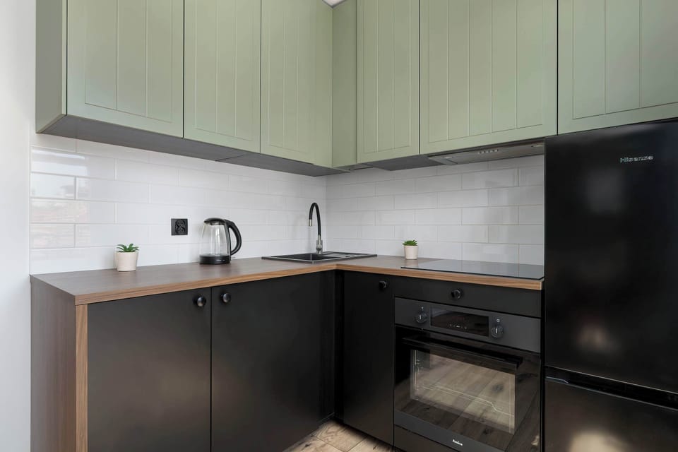 Sleek and minimal kitchen design with light green upper cabinets and dark base units. A perfect blend of functionality and aesthetics.
