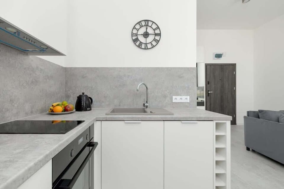 Compact kitchen area with white cabinets, a black backsplash, and essential appliances.