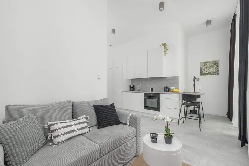 Living area with natural light from large windows, furnished with cozy seating and soft textiles.