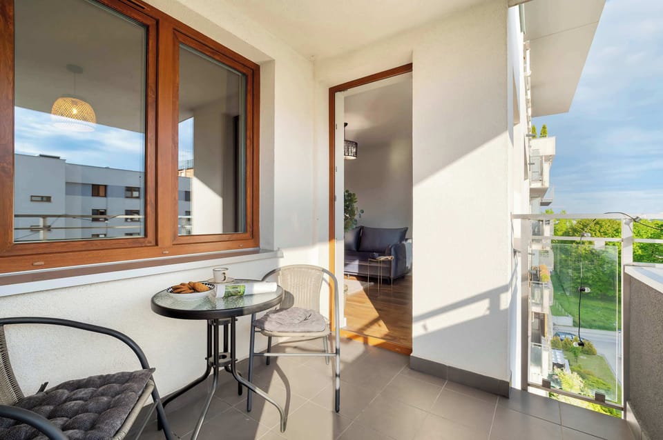 The balcony with a view of the green surroundings and equipped with a table and chairs invites spending time outdoors.