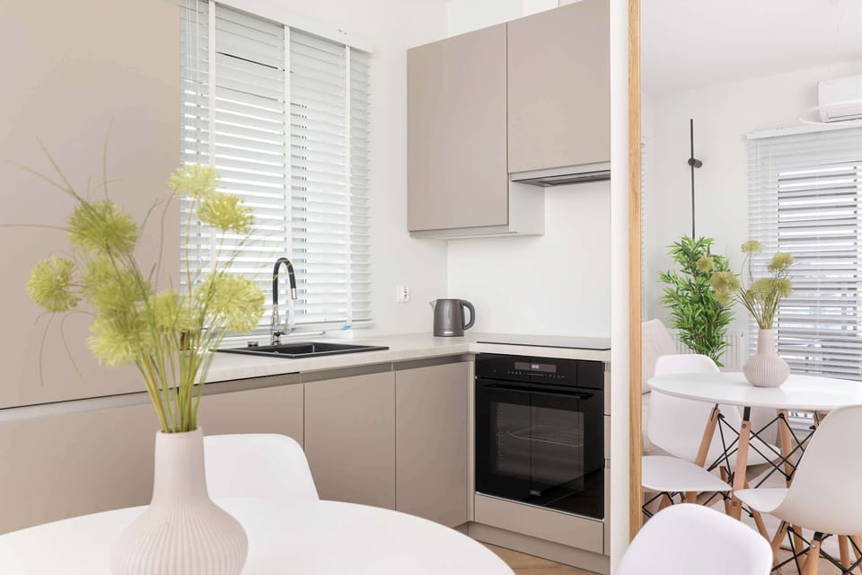 The kitchenette is fully equipped with a dishwasher, electric kettle, and a fridge with a freezer compartment. Its neutral design fits perfectly with the apartment's stylish decor.