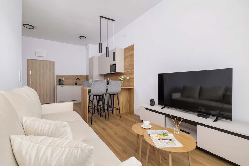 Living space combining a sitting area with a sofa and a dining space with modern chairs and a table. TV with a SmartTV+ option.