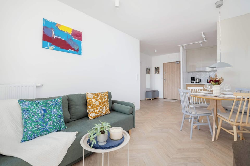 Living room with a sofa bed, TV, dining area, kitchenette and access to the balcony.