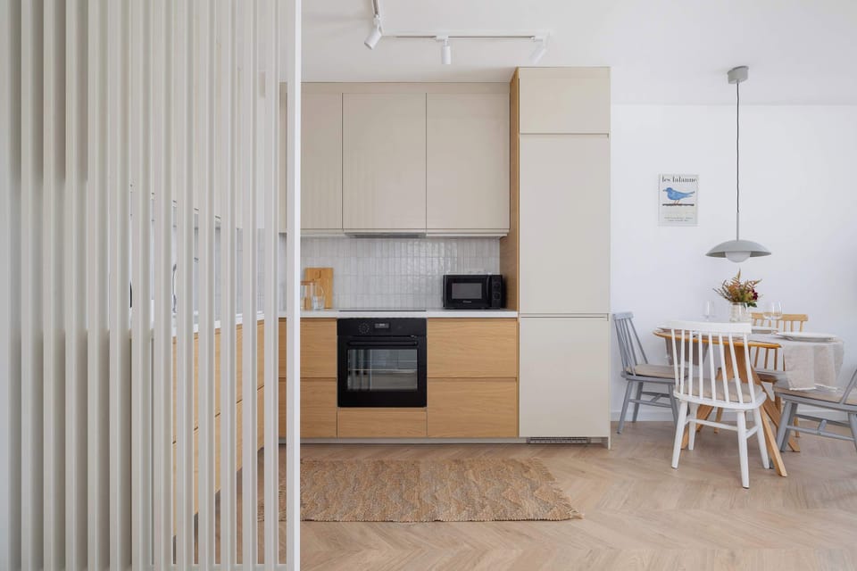 Fully equipped kitchenette with induction cooktop, oven, microwave, refrigerator with freezer, dishwasher, electric kettle, coffee maker and dining area.