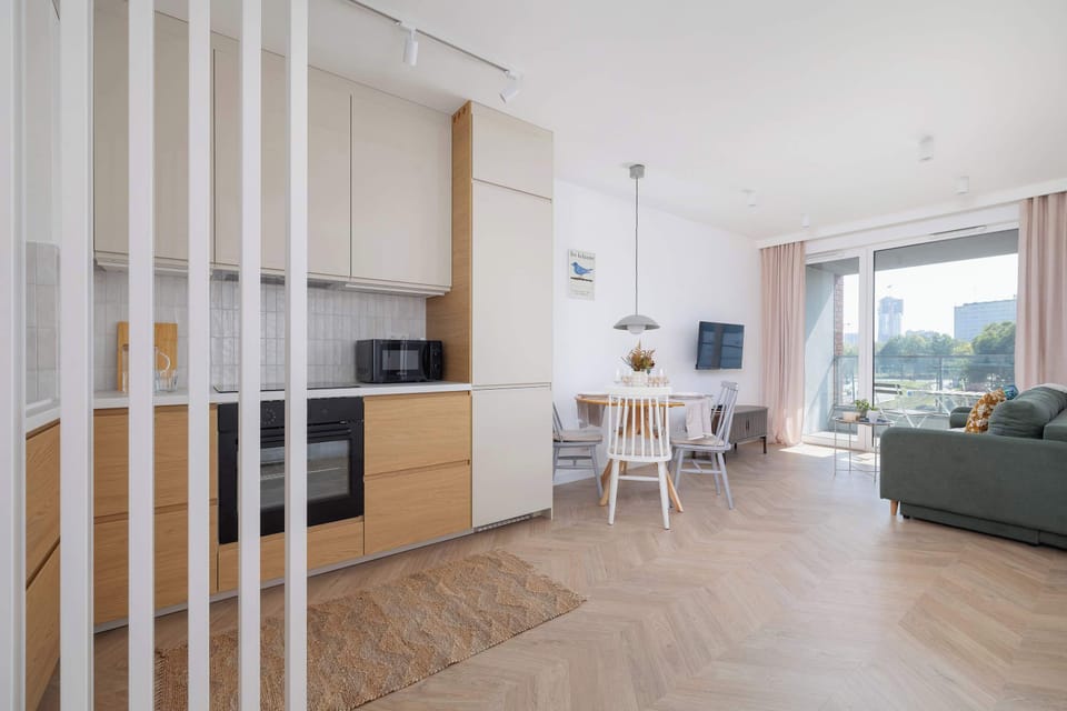 Spacious living room with a sofa bed, TV, dining area, kitchenette and access to the balcony.