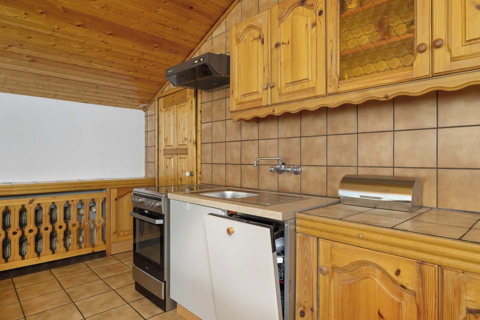  A fully equipped kitchen with wooden cabinets, tiled walls, and white appliances, combining rustic aesthetics with functionality.