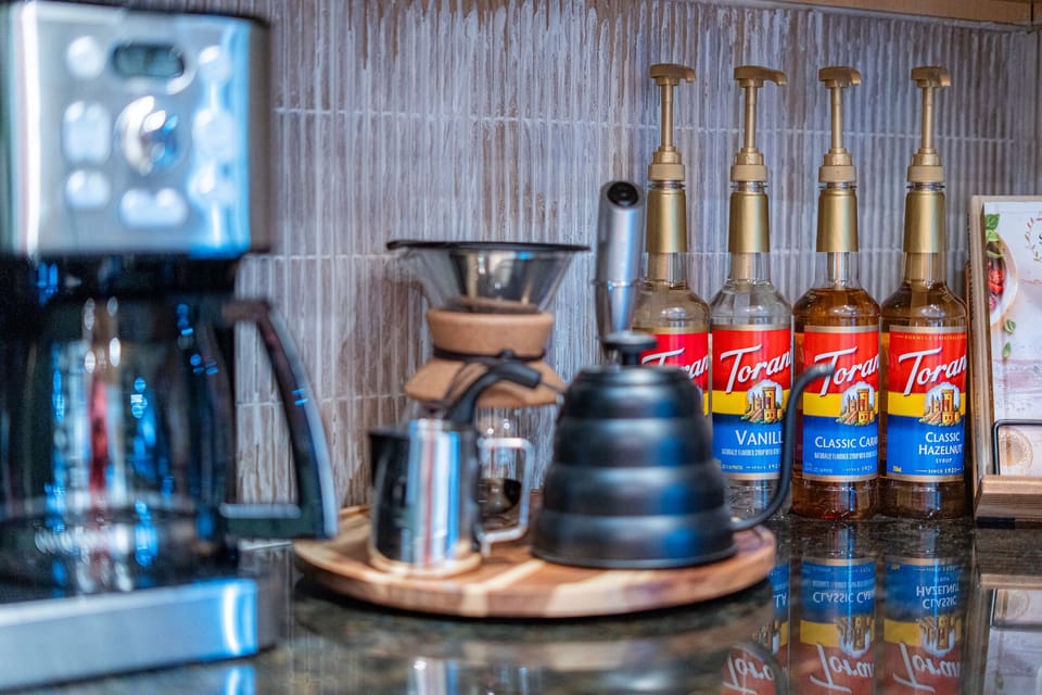 Fully stocked coffee bar with drip, pour-over, K-Cups, frother, and syrups