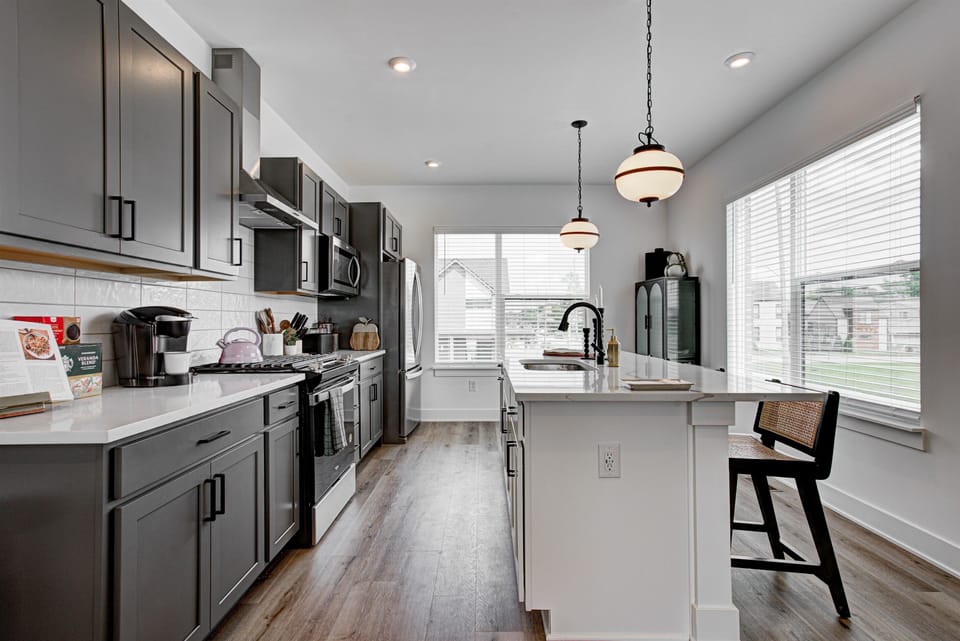 Enjoy a designed open-concept space with a modern kitchen equipped with quartz countertops, stainless steel appliances, and all essentials for home cooking. 