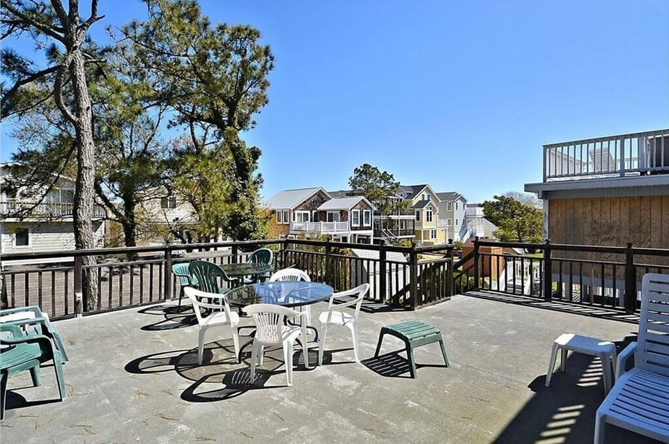 A spacious rooftop deck is equipped with a dining table and several chairs, surrounded by trees, perfect for enjoying the fresh air.