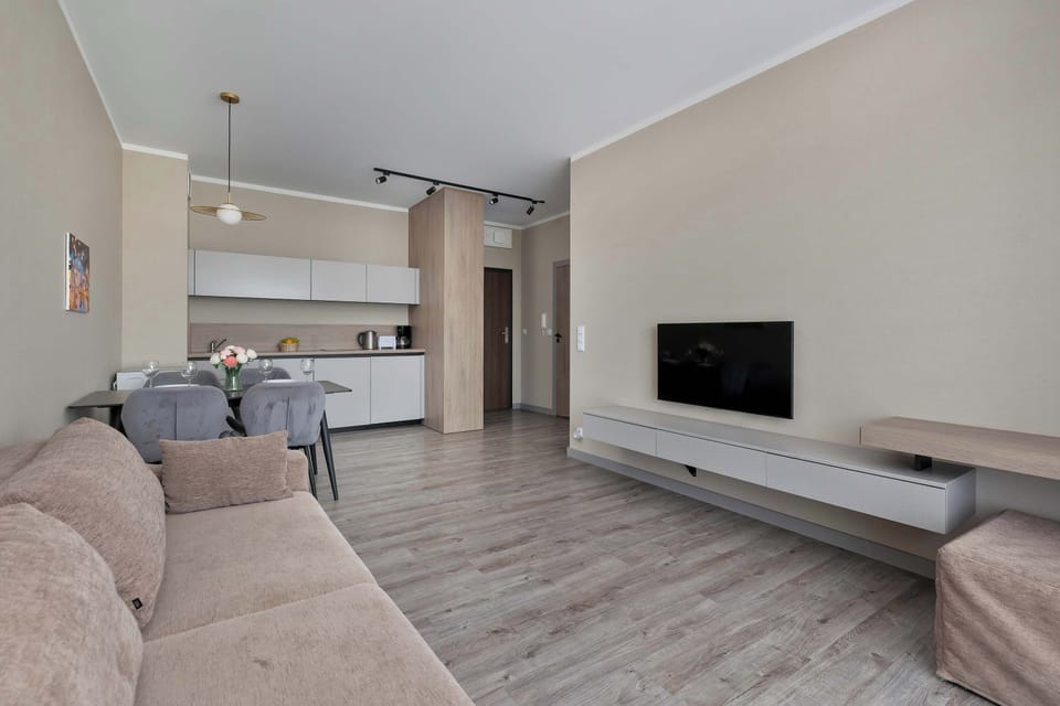 A spacious living room with modern decor, a comfortable corner sofa, and a large wall-mounted TV invites shared moments of relaxation.