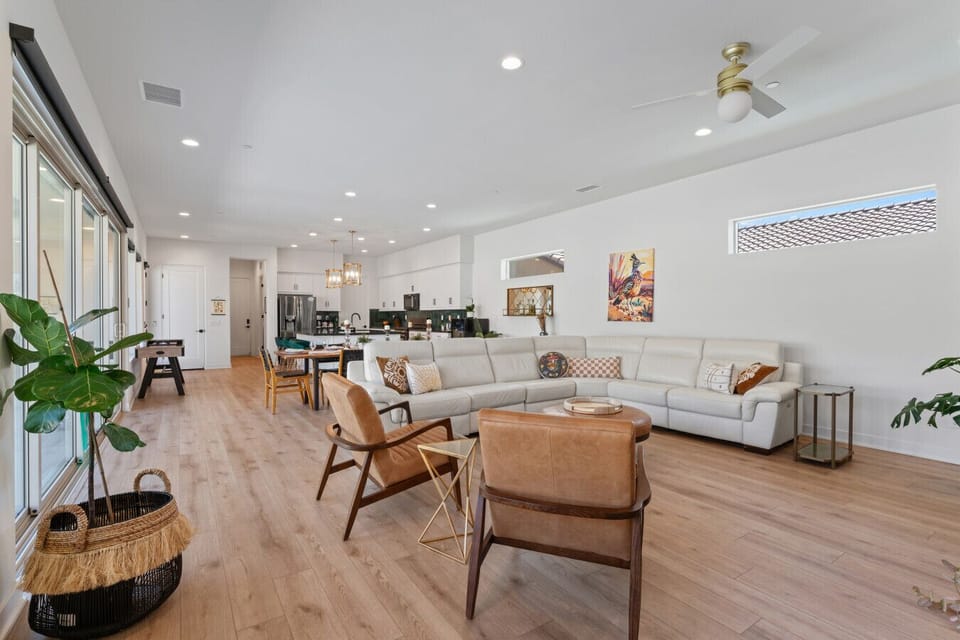 Open-concept living area w/ cozy seating, wall art & natural light pouring through large windows