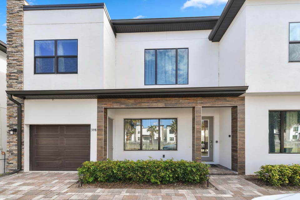 Modern two-story home with a garage and large windows overlooking the front yard