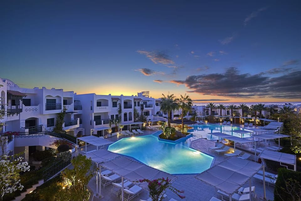 Unwind at sunset beside glowing lagoon pools and palms.